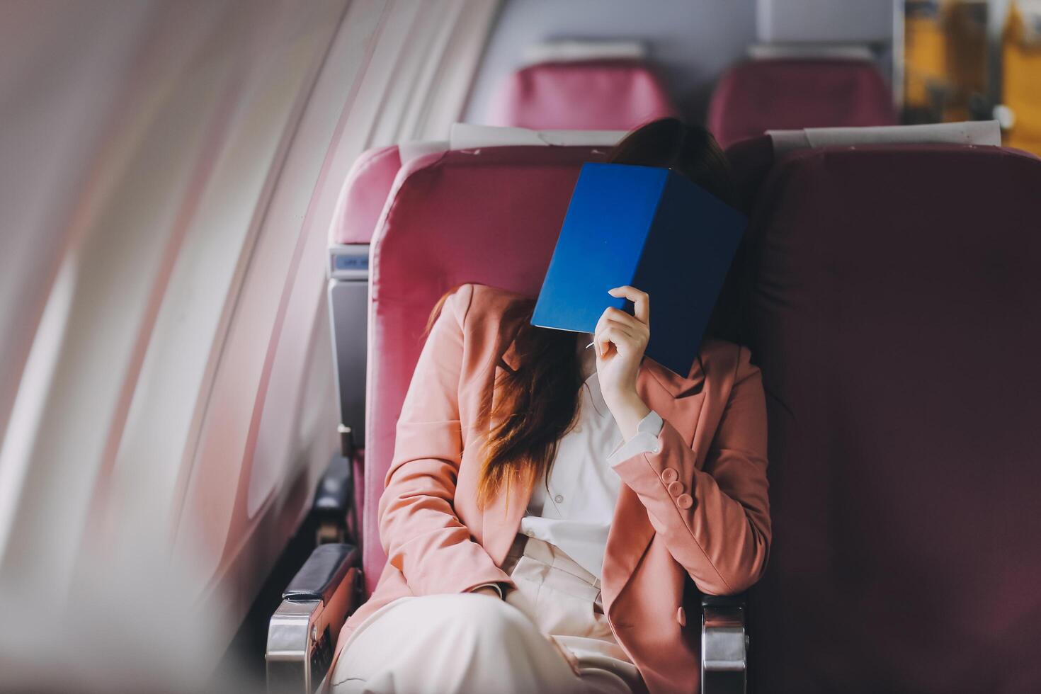 Tired asian woman with headache feeling sick while sitting in the airplane , Passengers near the window. photo
