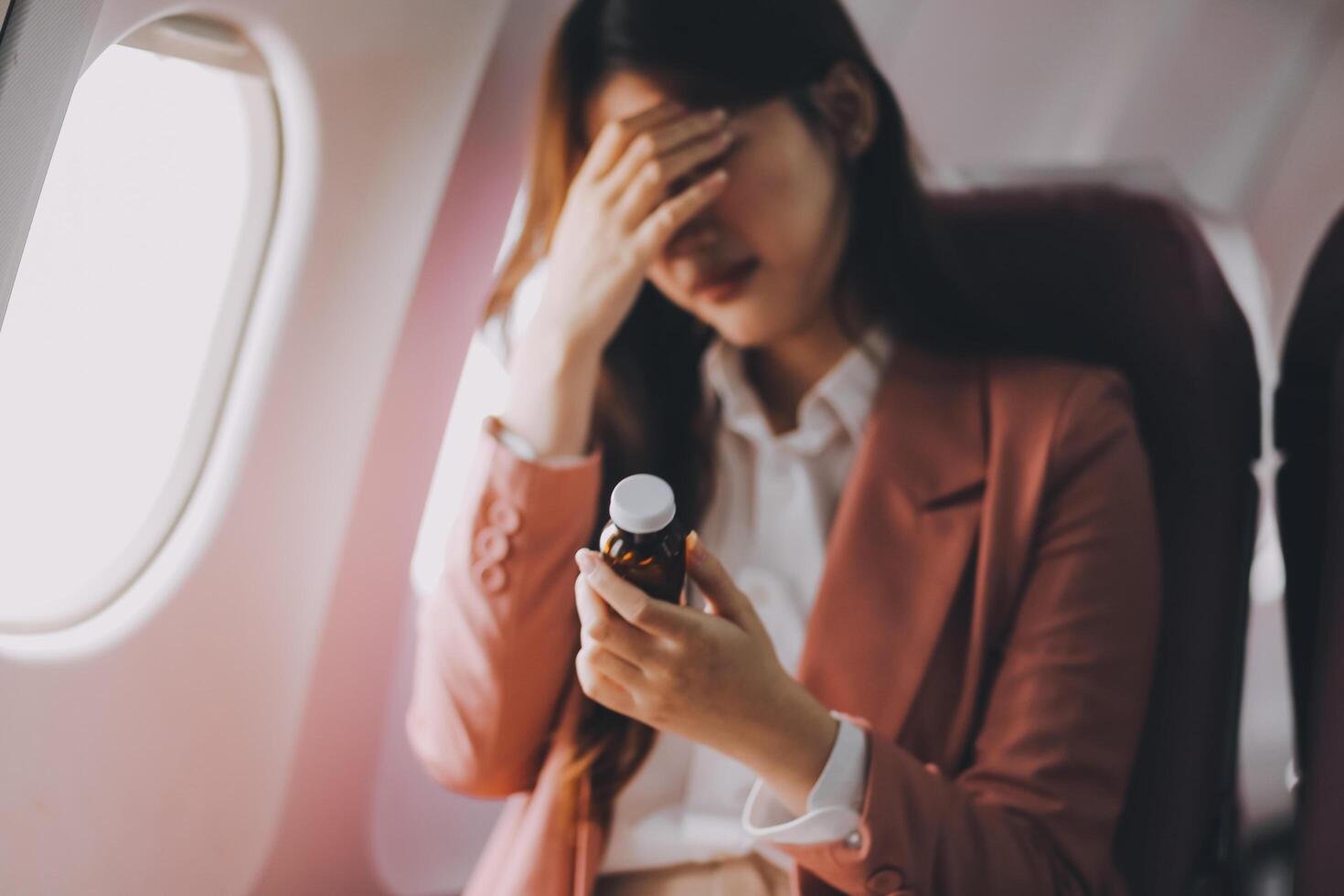 Tired asian woman with headache feeling sick while sitting in the airplane , Passengers near the window. photo