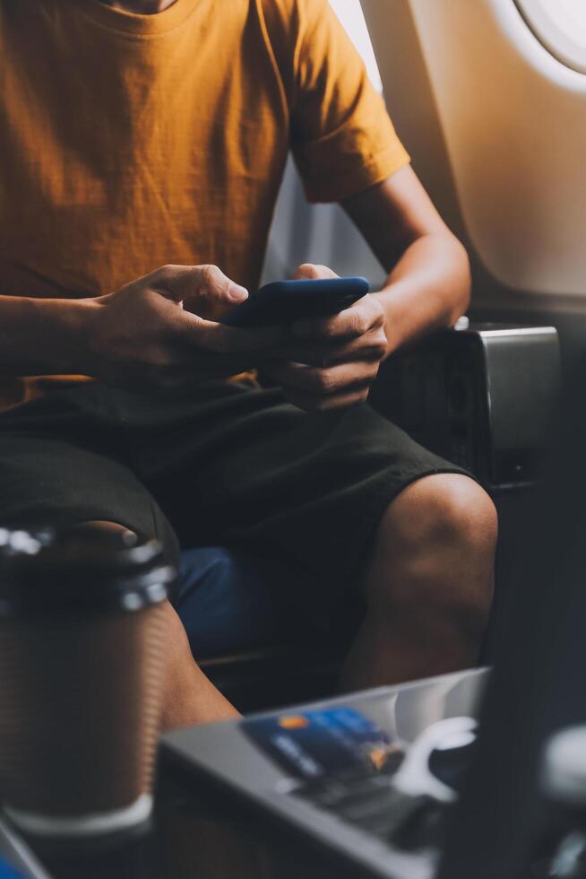 Attractive Asian businesswoman traveling on airplane playing with mobile phone while sitting in cabin. photo