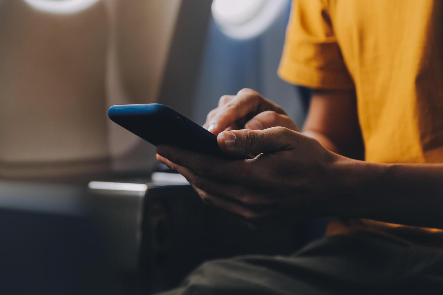 Attractive Asian businesswoman traveling on airplane playing with mobile phone while sitting in cabin. photo