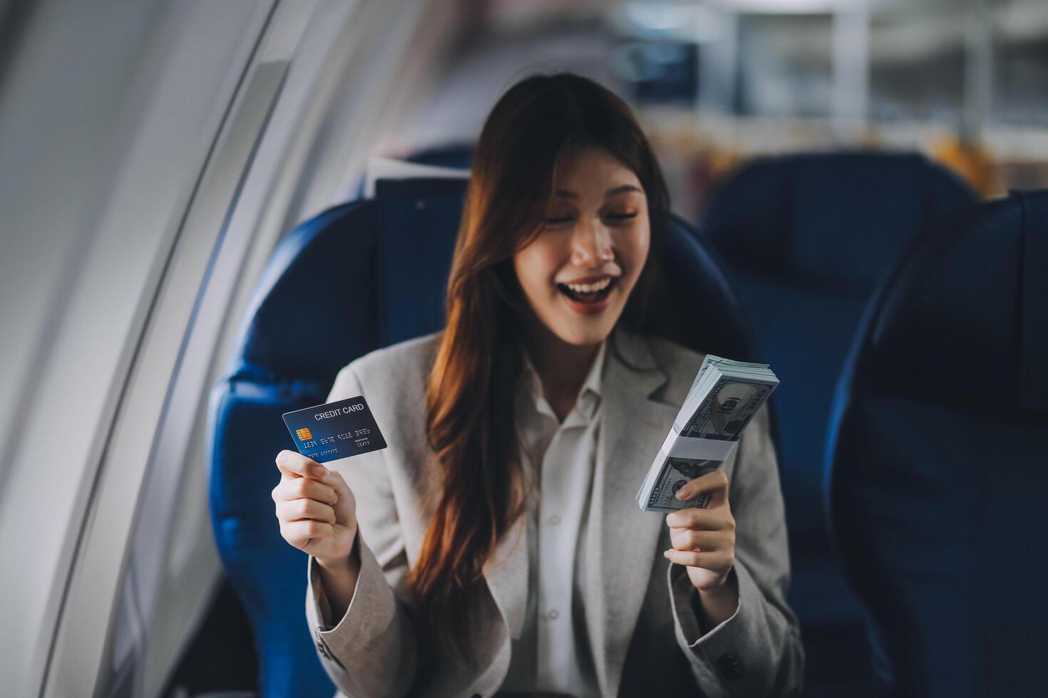 Young businesswoman holding credit card near blurred devices in private plane photo