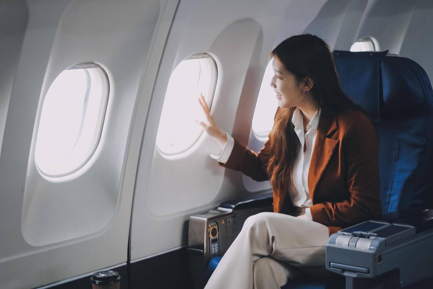 A female tourist is sitting inside a passenger plane, looking at the bird's eye view from the airplane window. photo