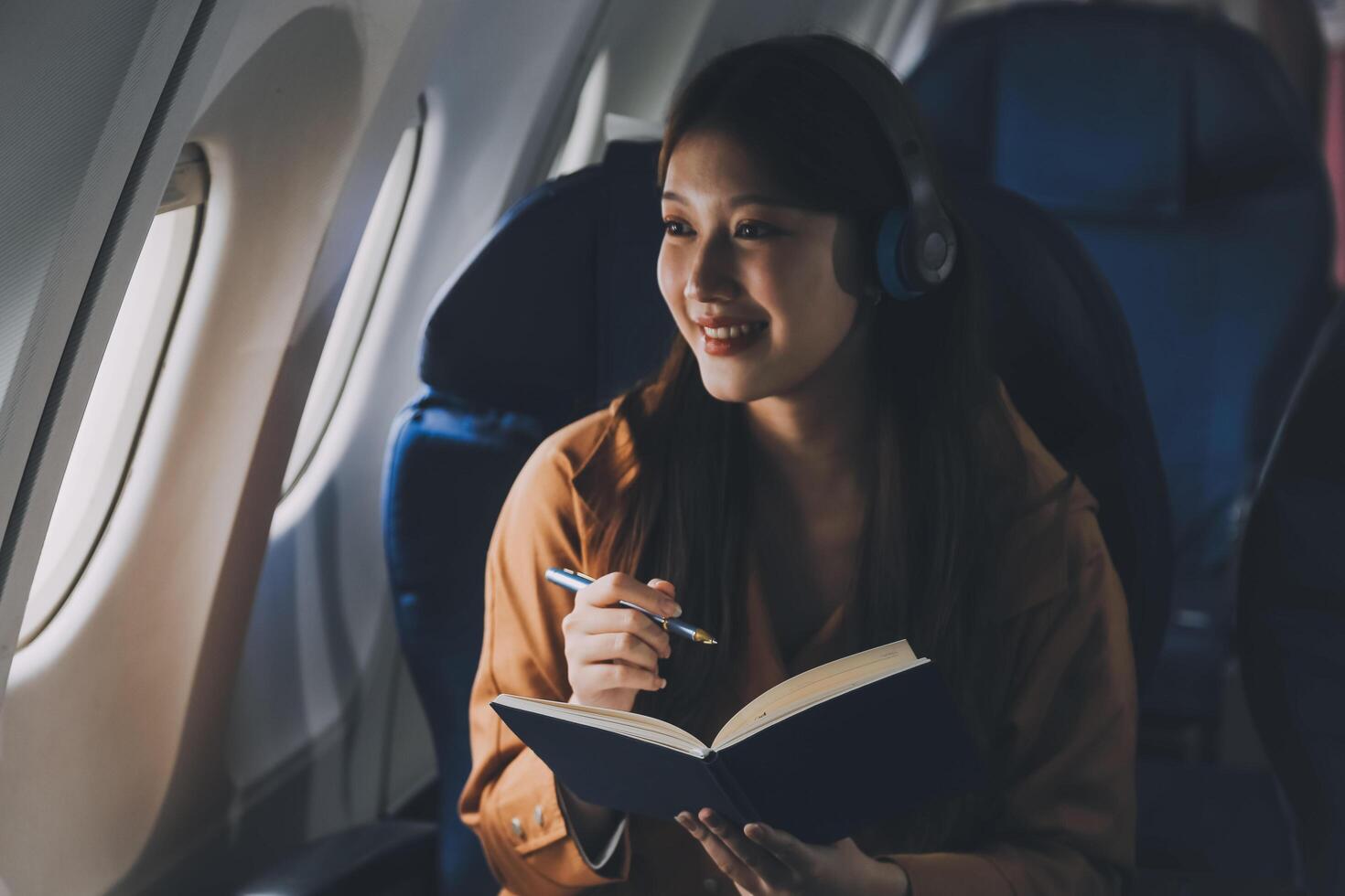 A young Asian woman, seated as an airplane passenger, contemplates dollar bills, reflecting on lucrative opportunities and aspirations towards billionaire status. photo