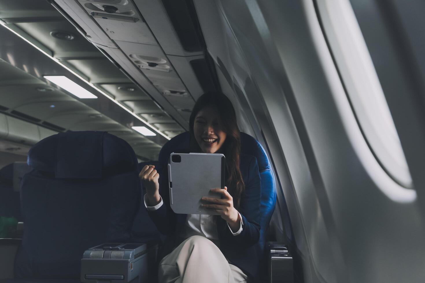 Young Asian executive excels in first class, multitasking with digital tablet, laptop and smartphone. Travel in style, work with grace. photo