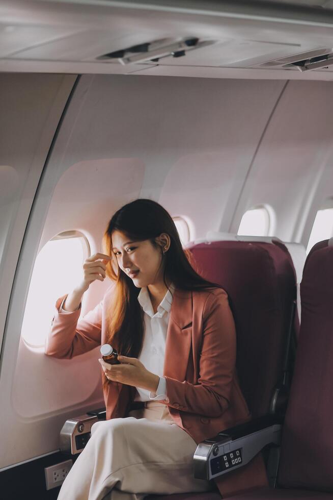 Tired asian woman with headache feeling sick while sitting in the airplane , Passengers near the window. photo