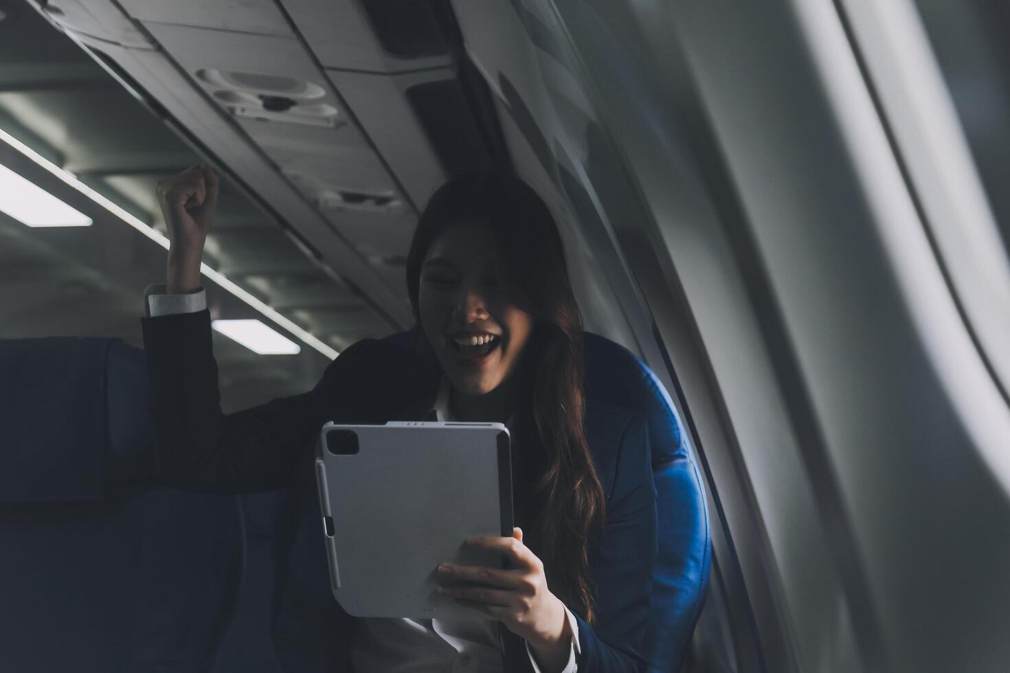 Young Asian executive excels in first class, multitasking with digital tablet, laptop and smartphone. Travel in style, work with grace. photo
