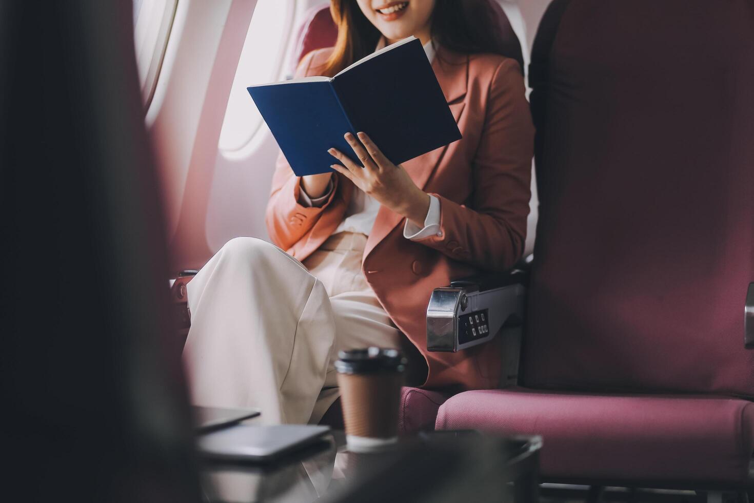 Attractive Asian female passenger of airplane sitting in comfortable seat while working laptop and tablet with mock up area using wireless connection. Travel in style, work with grace. photo