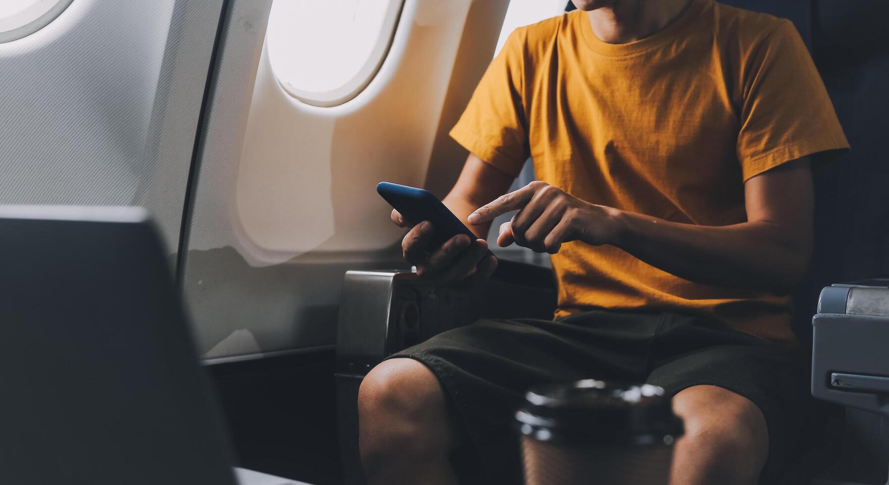 Attractive Asian businesswoman traveling on airplane playing with mobile phone while sitting in cabin. photo