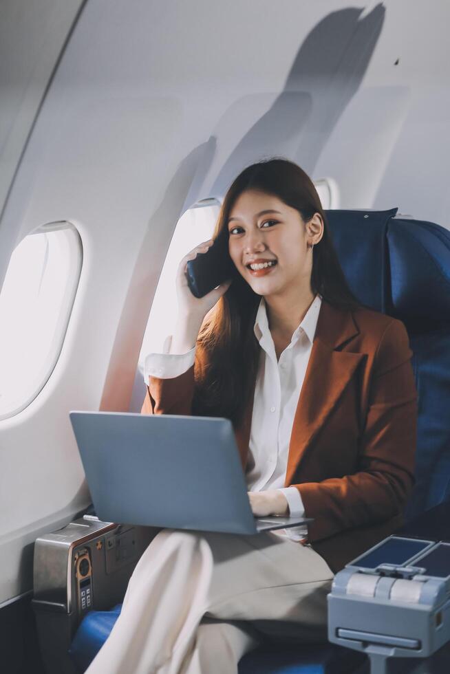 Young Asian executive excels in first class, multitasking with digital tablet, laptop and smartphone. Travel in style, work with grace. photo