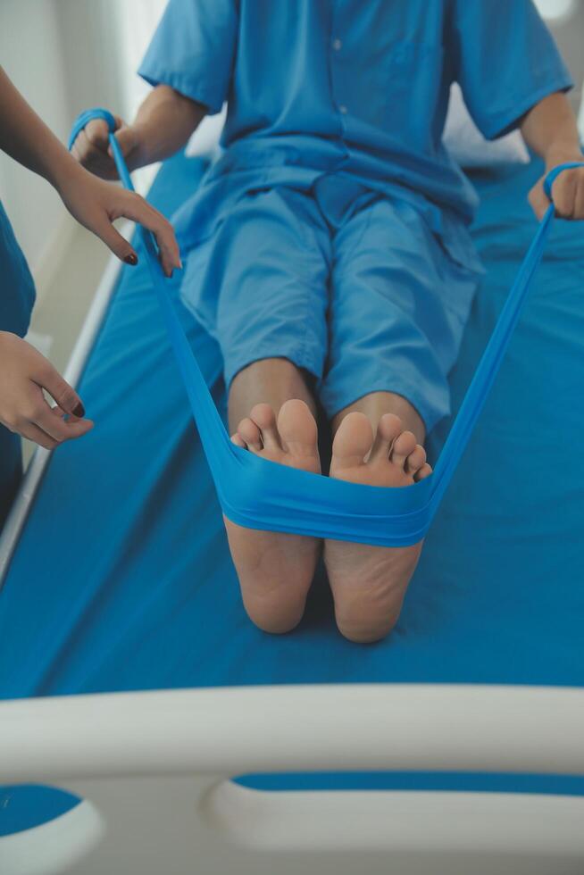 Professional orthopedist examining the little patient's leg in the clinic. Patient at the physiotherapy doing physical exercises with his therapist photo