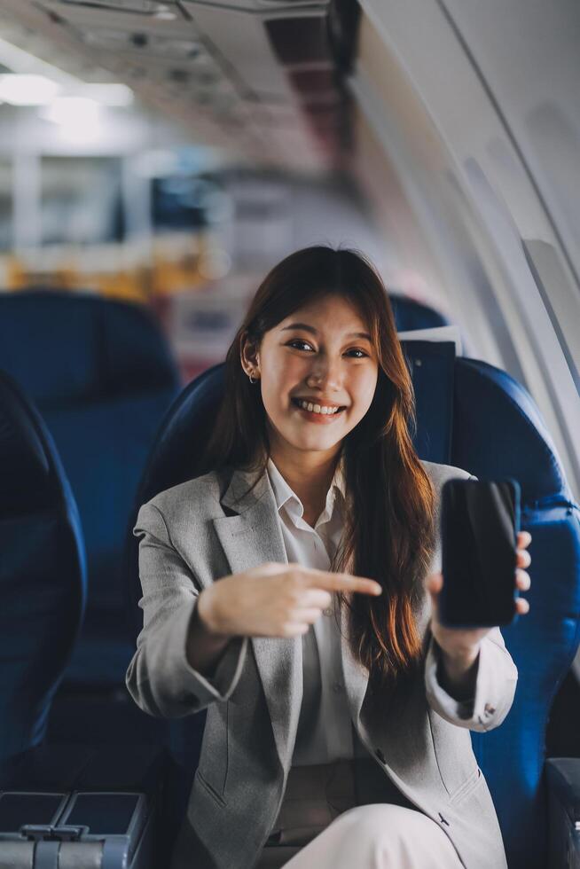 A young Asian woman, seated as an airplane passenger, contemplates dollar bills, reflecting on lucrative opportunities and aspirations towards billionaire status. photo