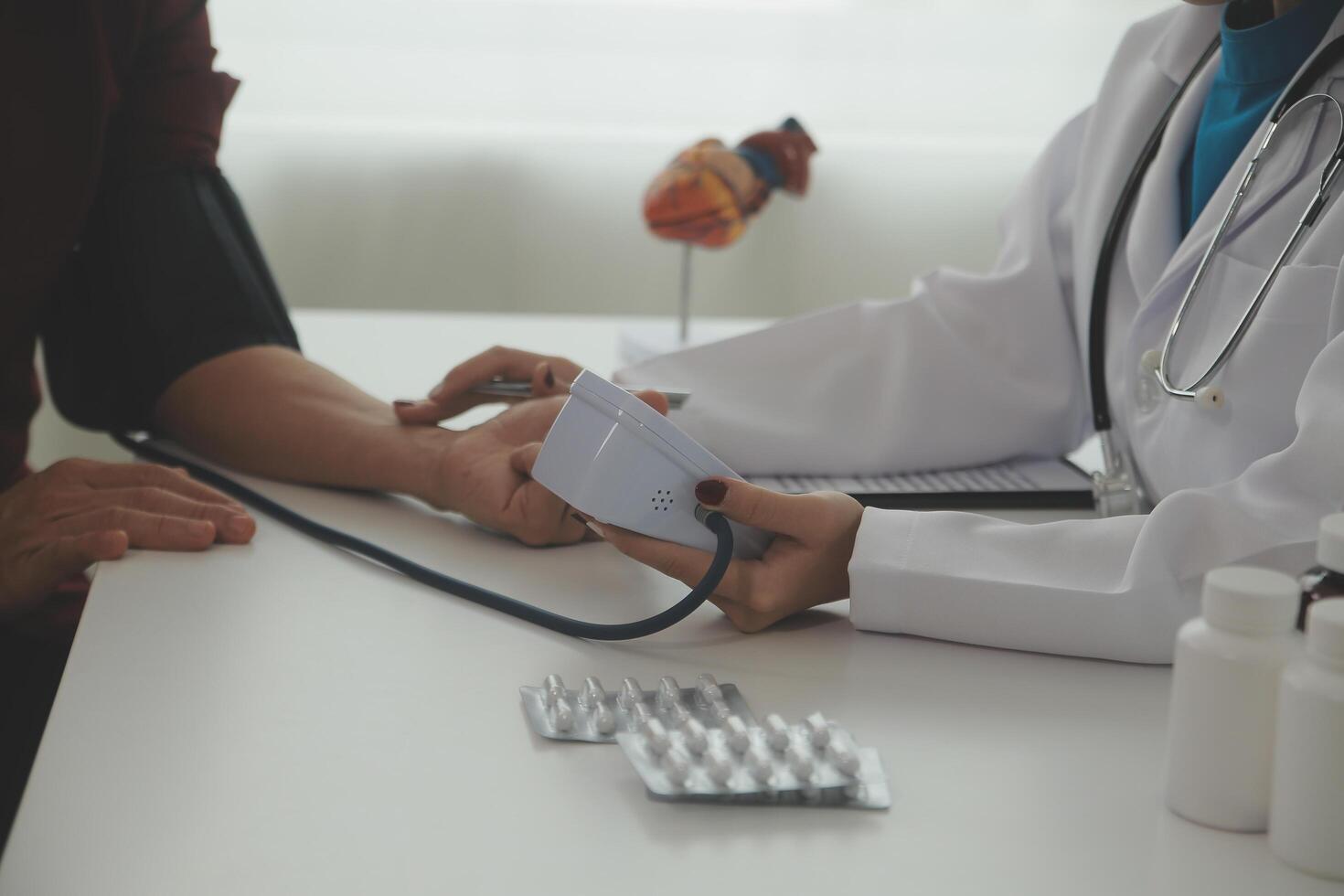 Doctor using sphygmomanometer with stethoscope checking blood pressure to a patient in the hospital. photo