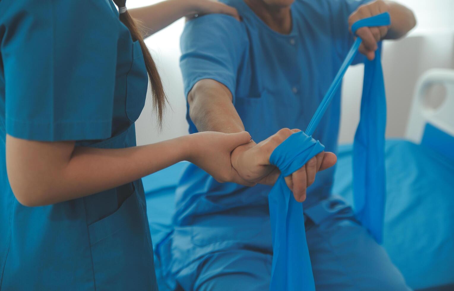 Close up hand patient doing stretching exercise with a flexible exercise band and a physical therapist hand to help in clinic room. photo