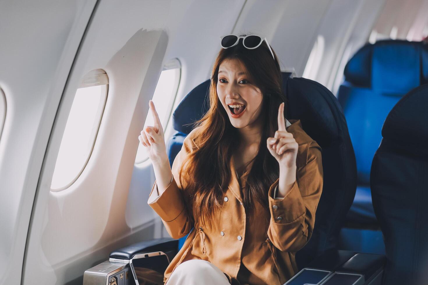 Joyful asian woman sits in the airplane and using tablet while go to travel photo