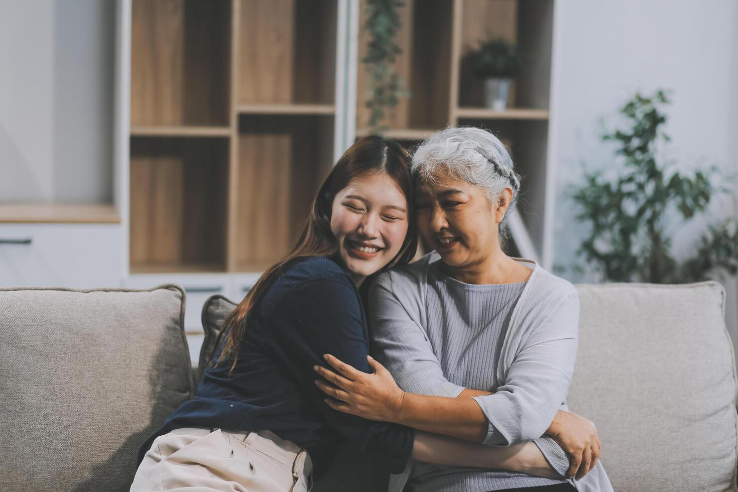 Adult daughter old mom hugging sit on couch enjoy pleasant positive talk, remembering funny occasion from life spend weekend together, caring about older generation relatives express attention concept photo