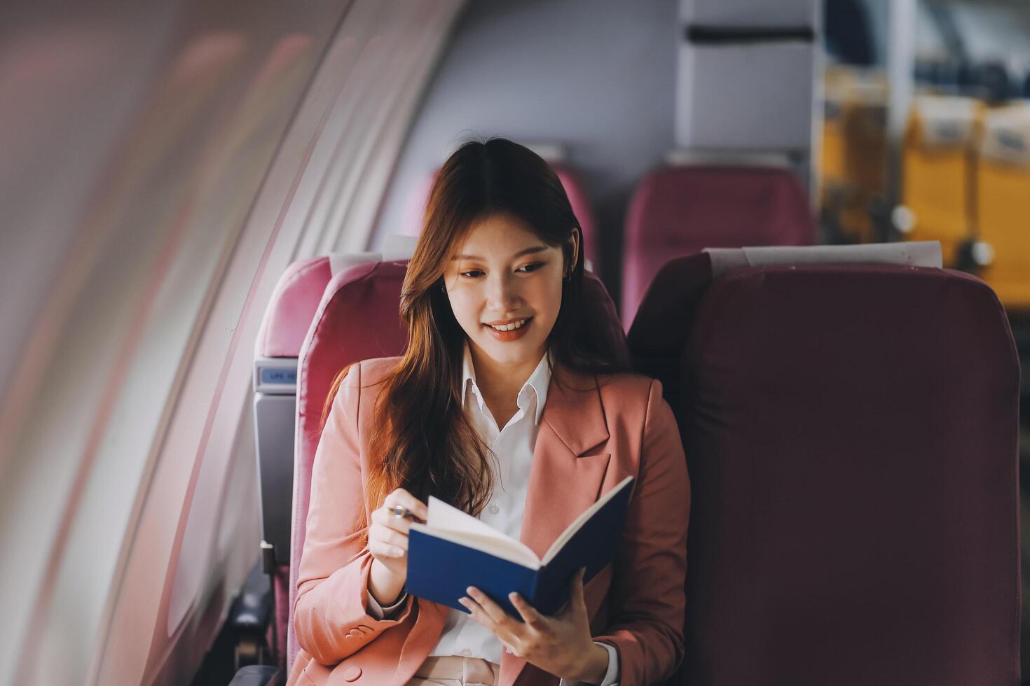 Attractive Asian female passenger of airplane sitting in comfortable seat while working laptop and tablet with mock up area using wireless connection. Travel in style, work with grace. photo
