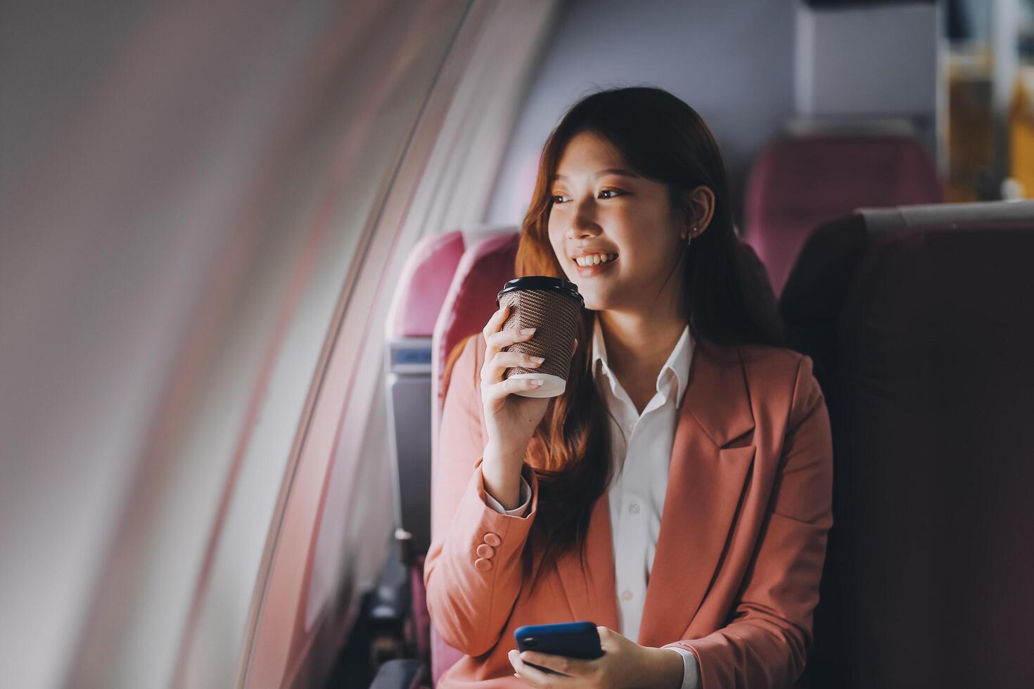 Attractive Asian female passenger of airplane sitting in comfortable seat while working laptop and tablet with mock up area using wireless connection. Travel in style, work with grace. photo