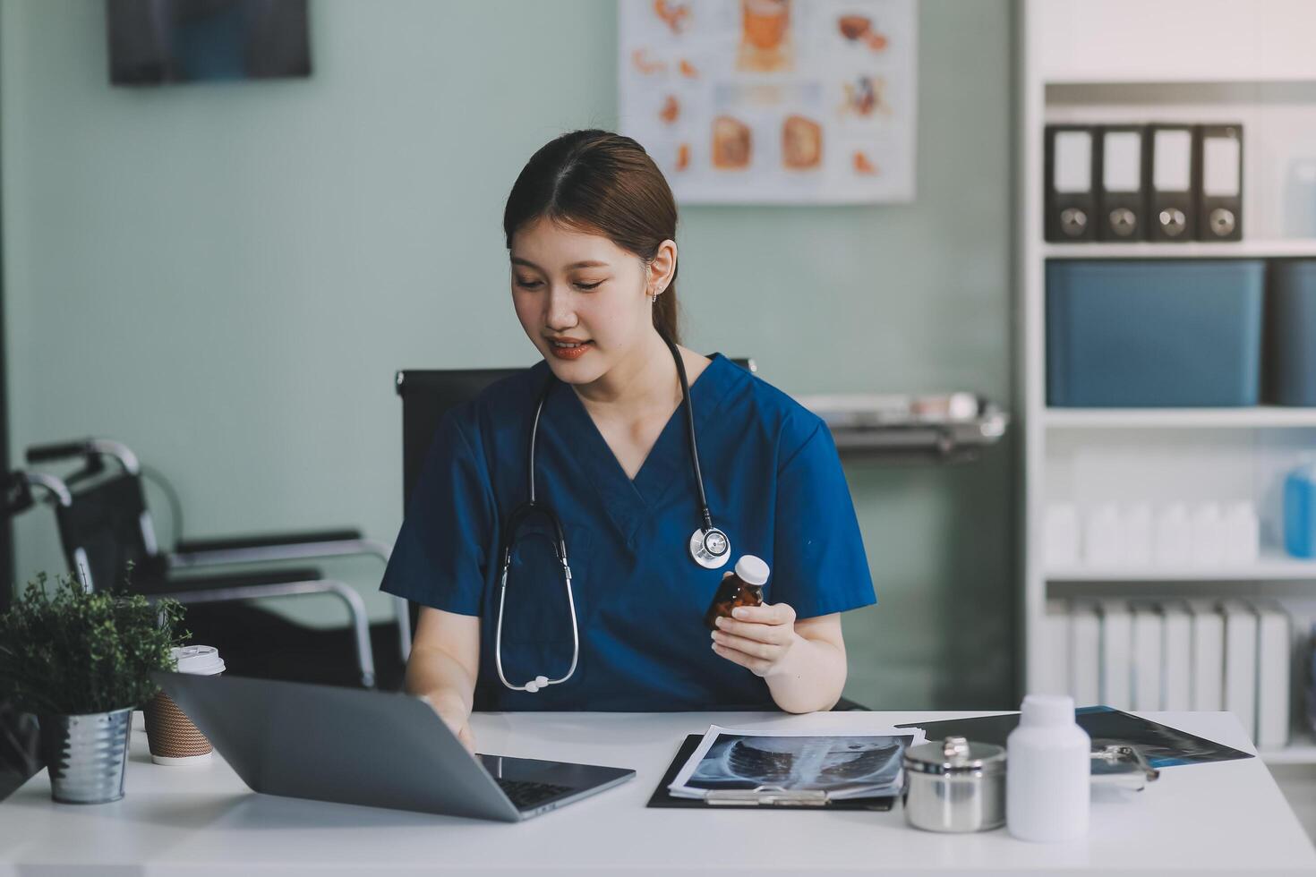 Female doctor writing in a notebook and holding a medicine bottle works at a computer while there were many medicine bottles on the table while sitting at a work desk photo