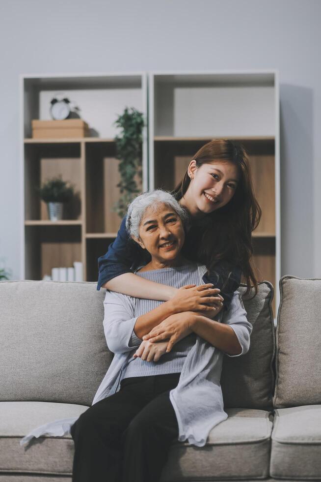 Adult daughter old mom hugging sit on couch enjoy pleasant positive talk, remembering funny occasion from life spend weekend together, caring about older generation relatives express attention concept photo