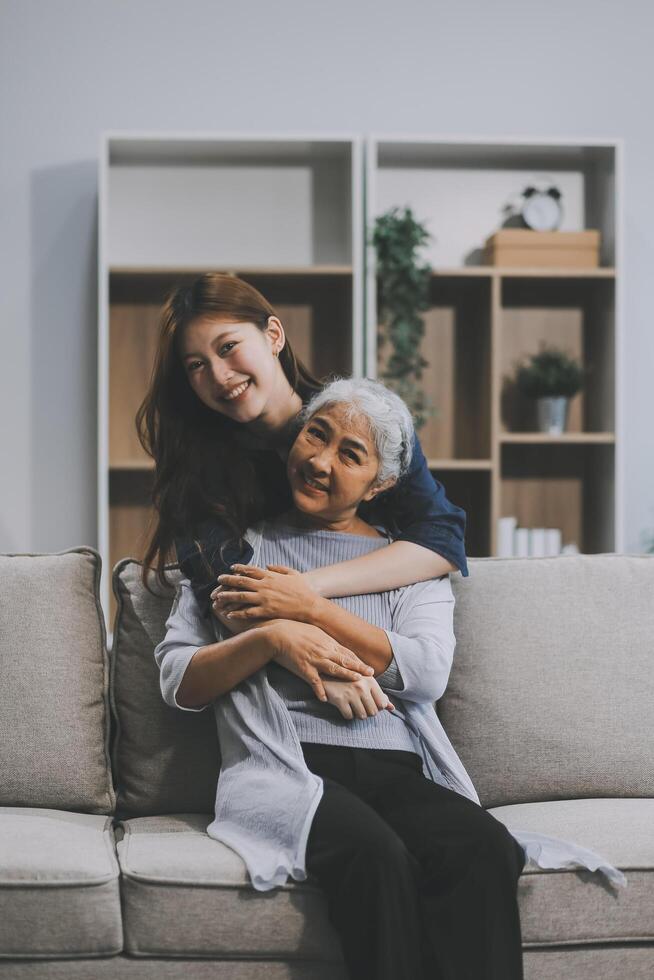 Adult daughter old mom hugging sit on couch enjoy pleasant positive talk, remembering funny occasion from life spend weekend together, caring about older generation relatives express attention concept photo