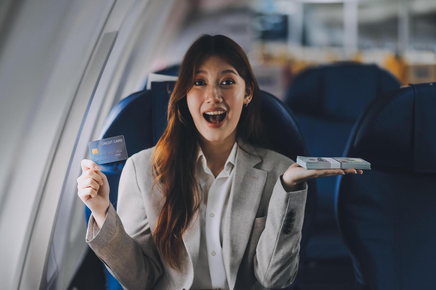 Young businesswoman holding credit card near blurred devices in private plane photo