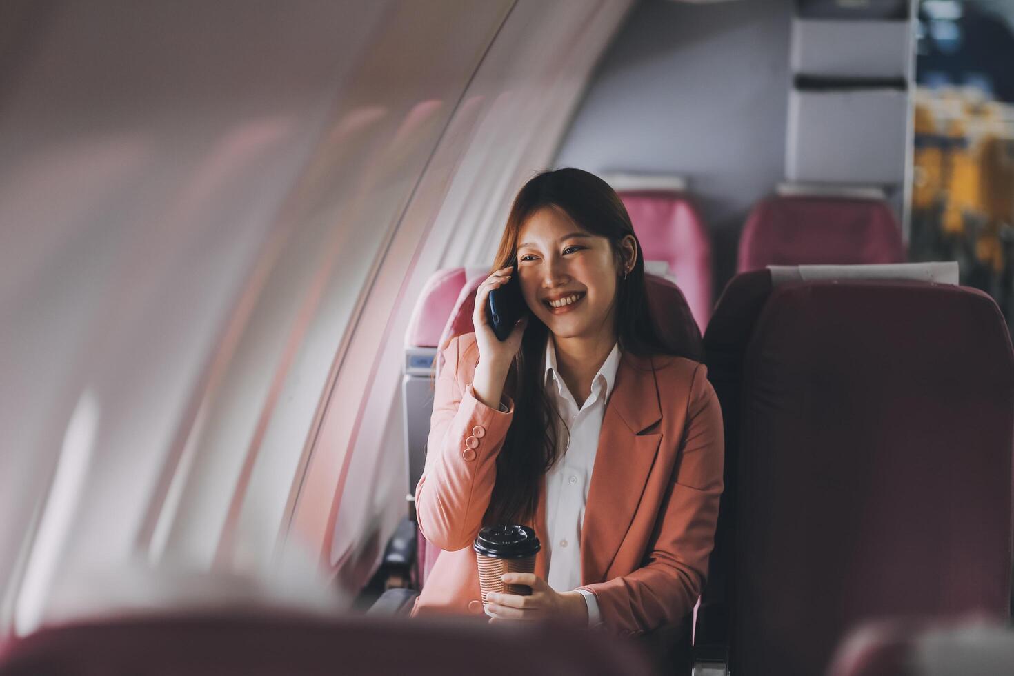 Attractive Asian female passenger of airplane sitting in comfortable seat while working laptop and tablet with mock up area using wireless connection. Travel in style, work with grace. photo