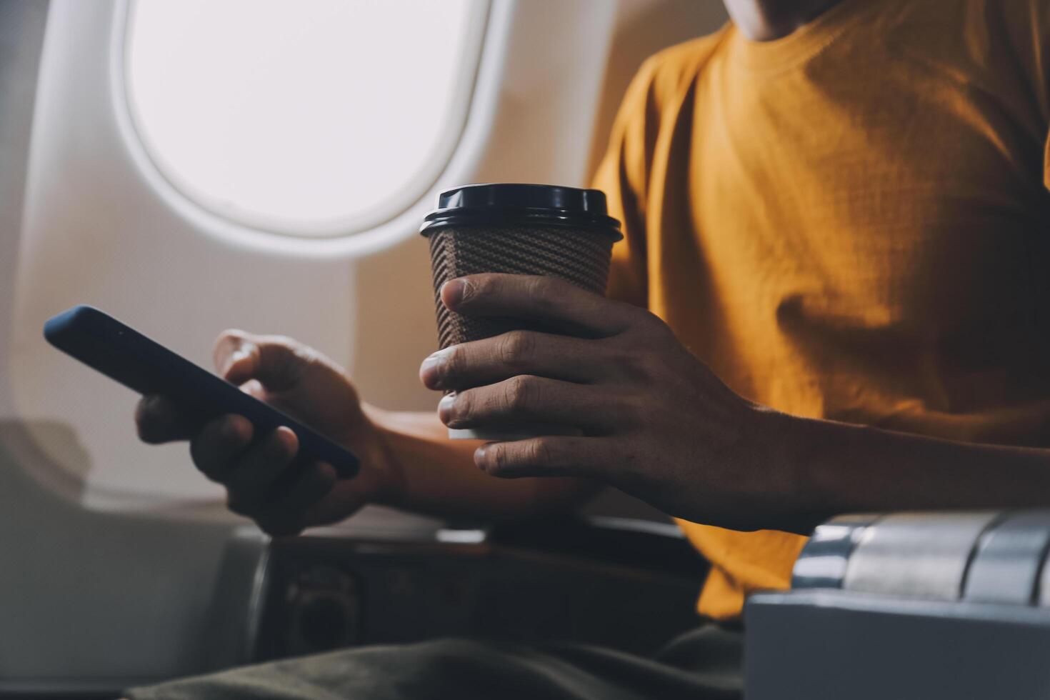 Attractive Asian businesswoman traveling on airplane playing with mobile phone while sitting in cabin. photo