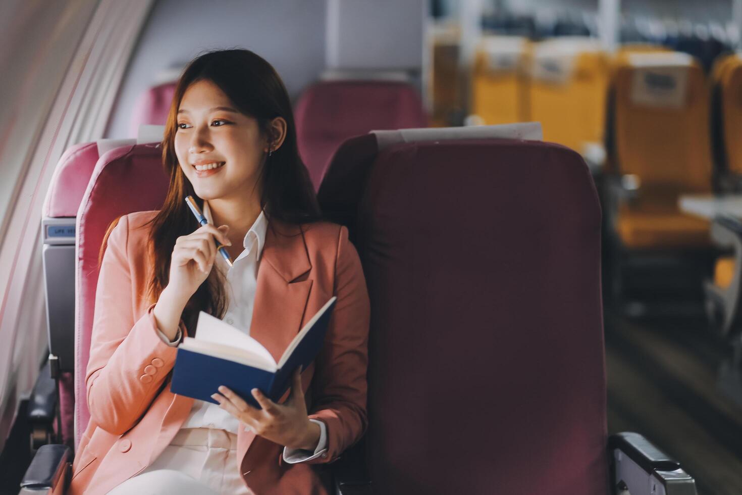 Attractive Asian female passenger of airplane sitting in comfortable seat while working laptop and tablet with mock up area using wireless connection. Travel in style, work with grace. photo