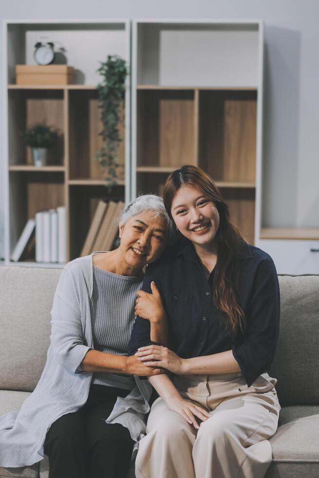 Adult daughter old mom hugging sit on couch enjoy pleasant positive talk, remembering funny occasion from life spend weekend together, caring about older generation relatives express attention concept photo