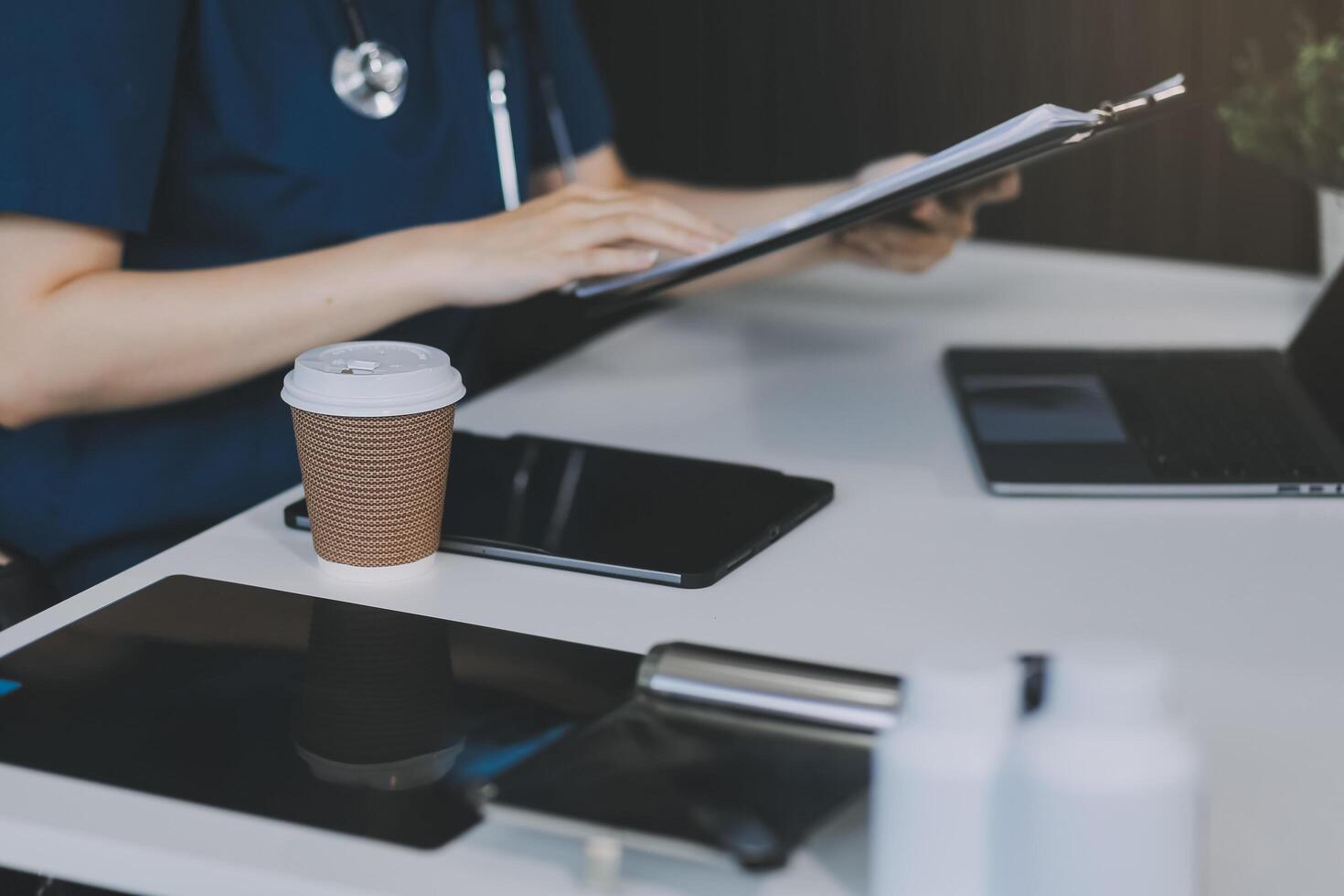 Female doctor writing in a notebook and holding a medicine bottle works at a computer while there were many medicine bottles on the table while sitting at a work desk photo