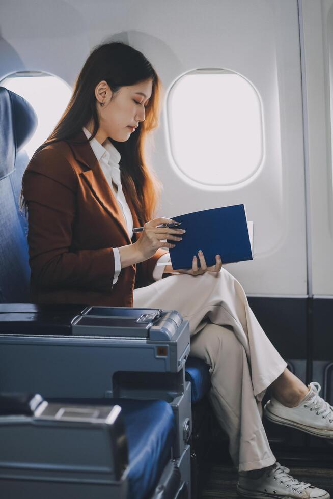 Young Asian executive excels in first class, multitasking with digital tablet, laptop and smartphone. Travel in style, work with grace. photo
