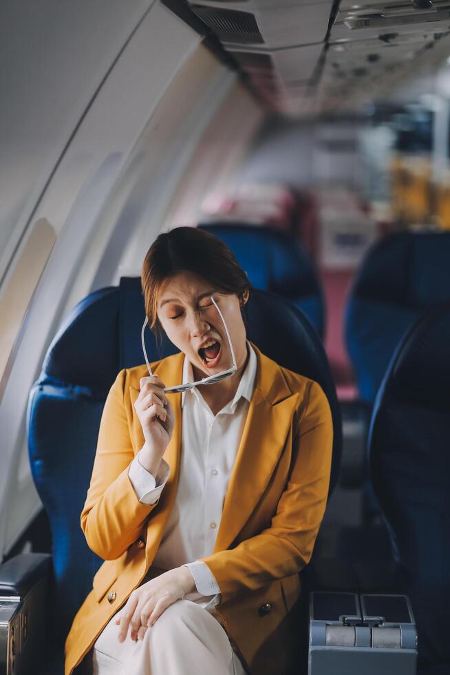 A young Asian woman, seated as an airplane passenger, contemplates dollar bills, reflecting on lucrative opportunities and aspirations towards billionaire status. photo