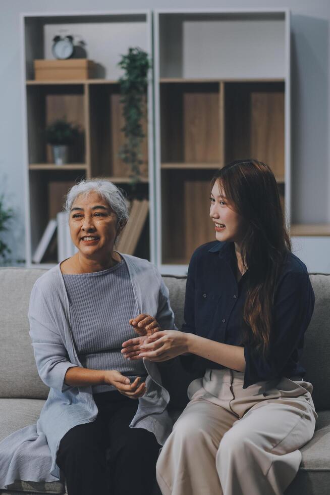 Adult daughter old mom hugging sit on couch enjoy pleasant positive talk, remembering funny occasion from life spend weekend together, caring about older generation relatives express attention concept photo