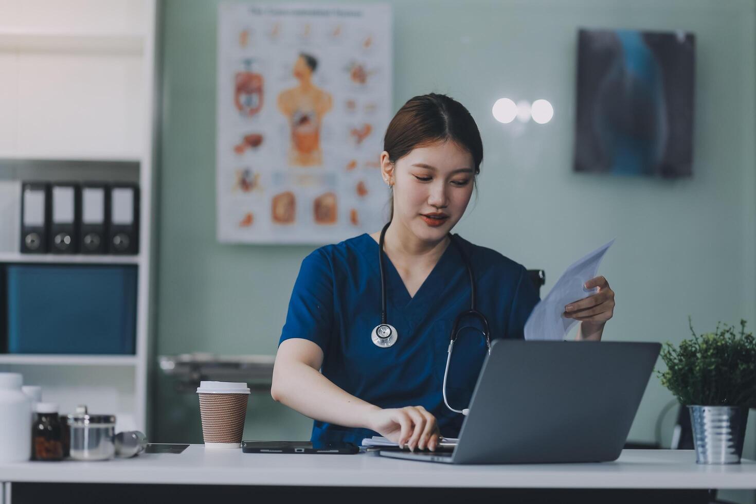 Female doctor writing in a notebook and holding a medicine bottle works at a computer while there were many medicine bottles on the table while sitting at a work desk photo