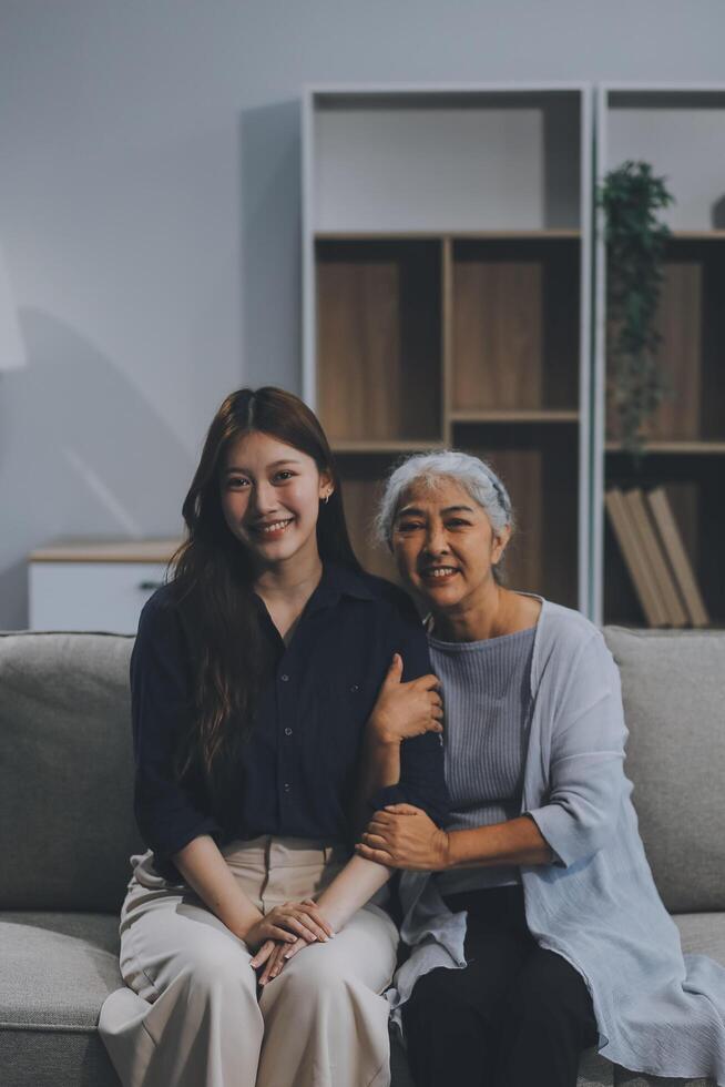 Adult daughter old mom hugging sit on couch enjoy pleasant positive talk, remembering funny occasion from life spend weekend together, caring about older generation relatives express attention concept photo