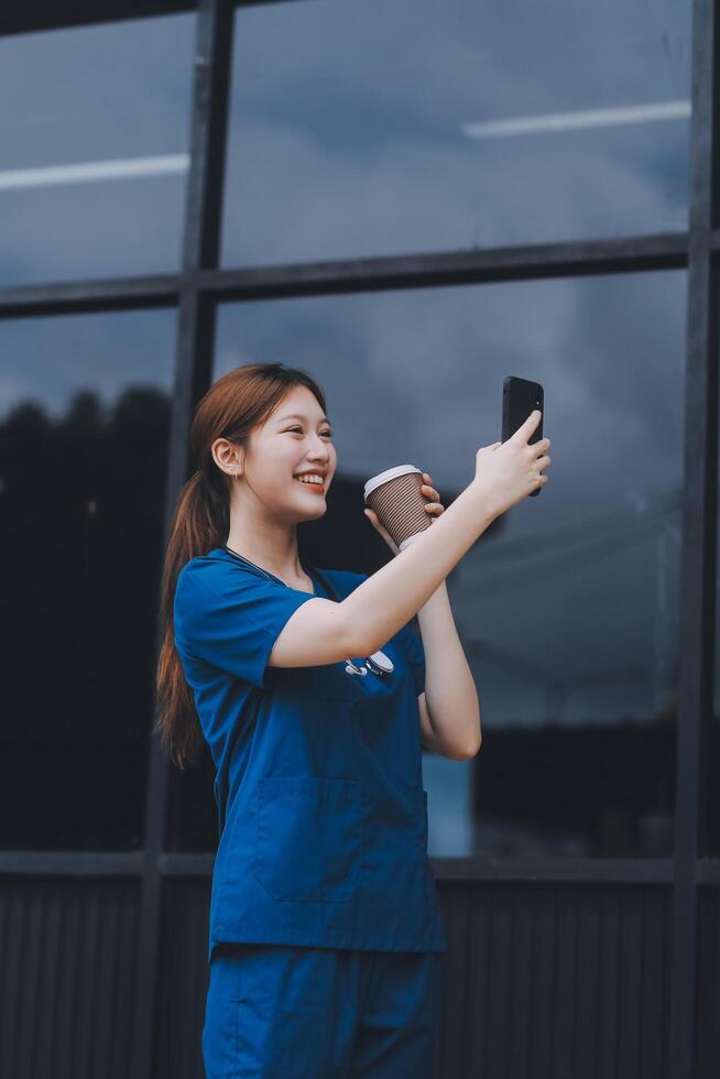 Confident nurse on her way to work in a clinic. Pretty female nurse drinking coffee and rest after hard work. The young adult female nurse drinks her coffee as she arrives to work at the hospital. photo