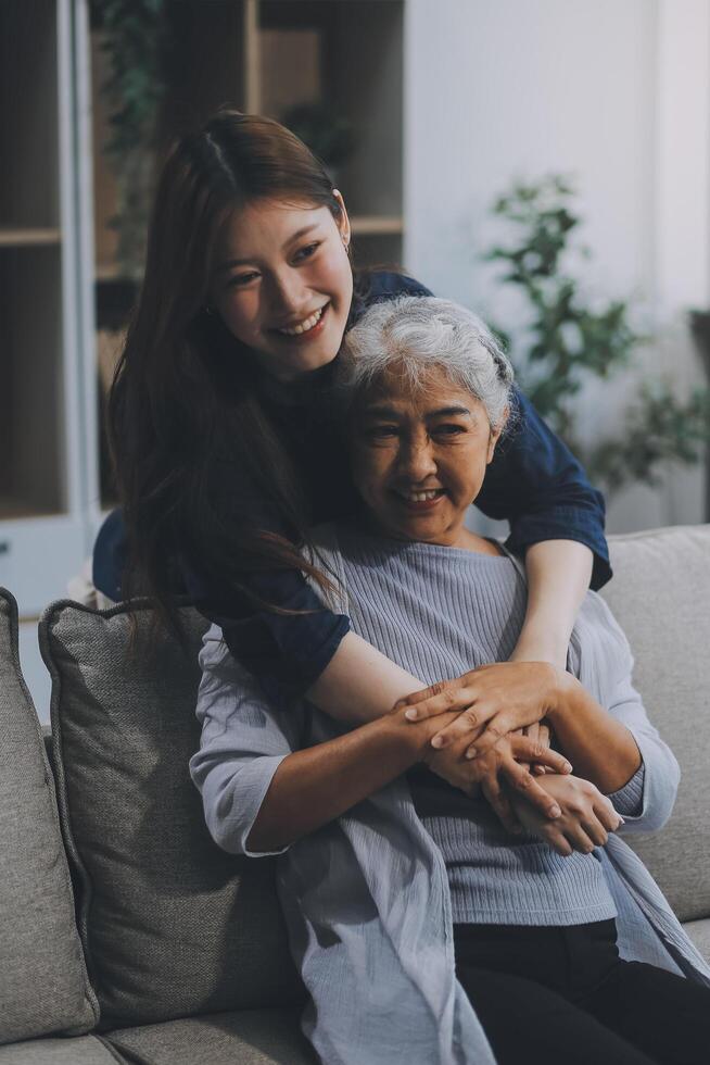Adult daughter old mom hugging sit on couch enjoy pleasant positive talk, remembering funny occasion from life spend weekend together, caring about older generation relatives express attention concept photo