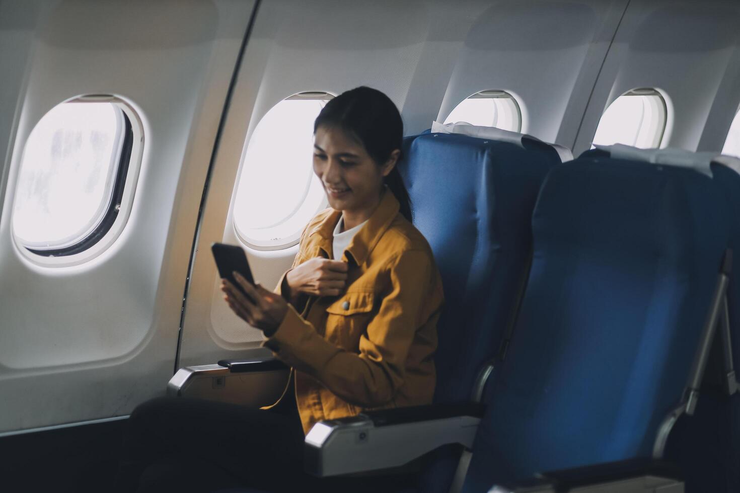 Texting on mobile chat app, Thoughtful asian people female person onboard, airplane window, perfectly capture the anticipation and excitement of holiday travel. chinese, japanese people. photo