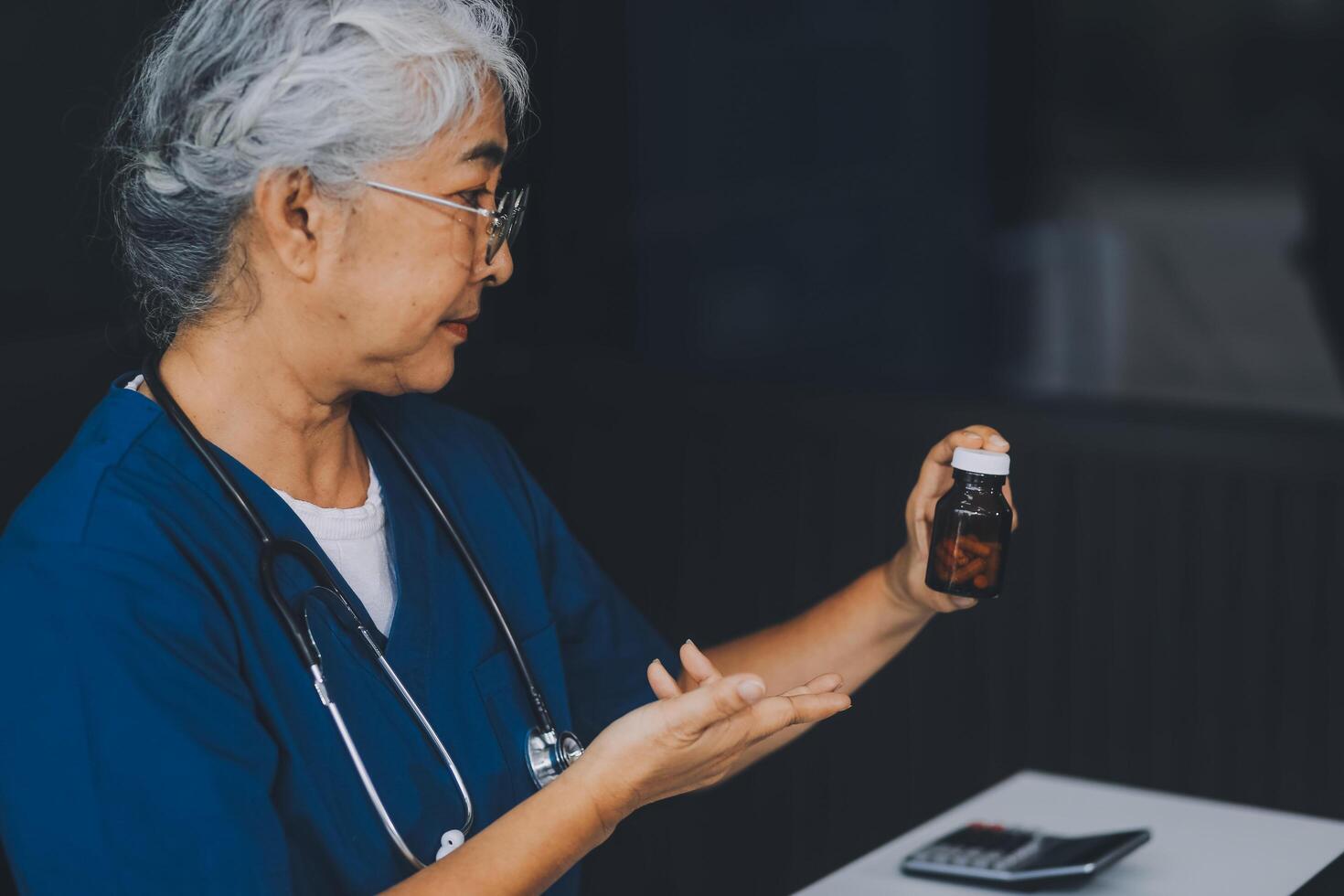 A woman doctor is writing on a clipboard and holding a bottle of pills. She is smiling and seems to be in a good mood photo