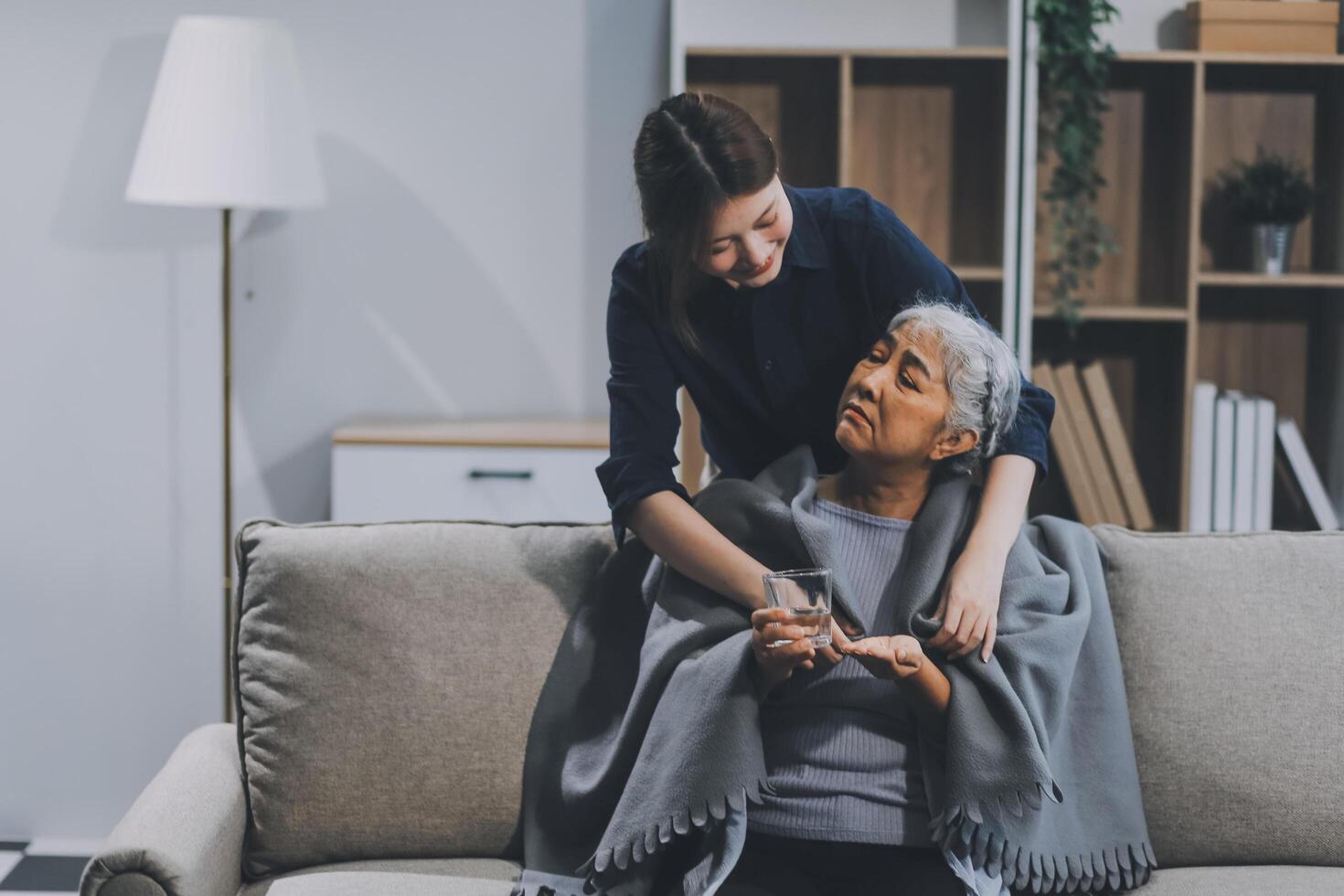happy family Granddaughter takes care of her grandmother with warm cloths sitting on the sofa. photo