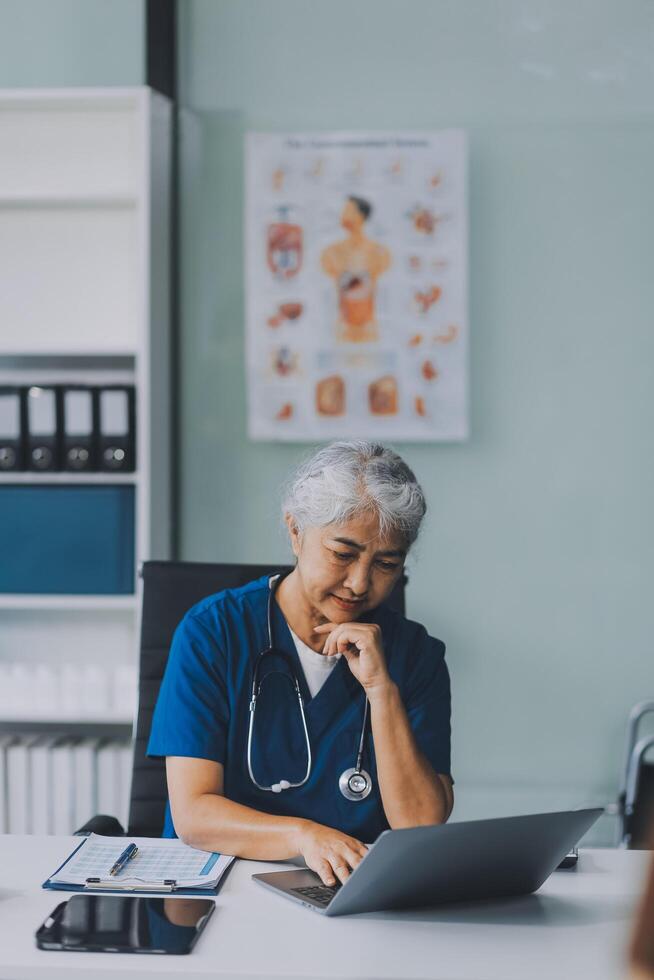 Thoughtful Hispanic female doctor sitting at her desk in a bright medical office, looking at a laptop screen. photo