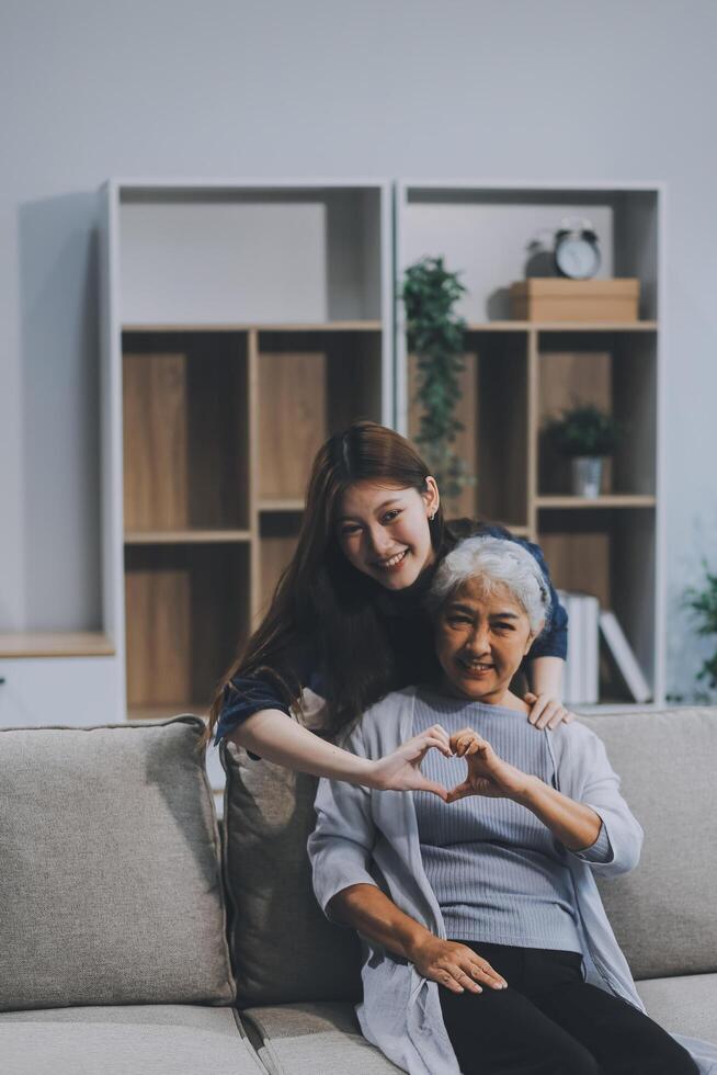 Adult daughter old mom hugging sit on couch enjoy pleasant positive talk, remembering funny occasion from life spend weekend together, caring about older generation relatives express attention concept photo