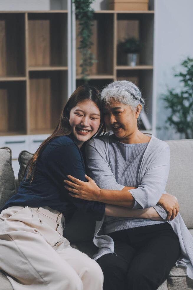 Adult daughter old mom hugging sit on couch enjoy pleasant positive talk, remembering funny occasion from life spend weekend together, caring about older generation relatives express attention concept photo