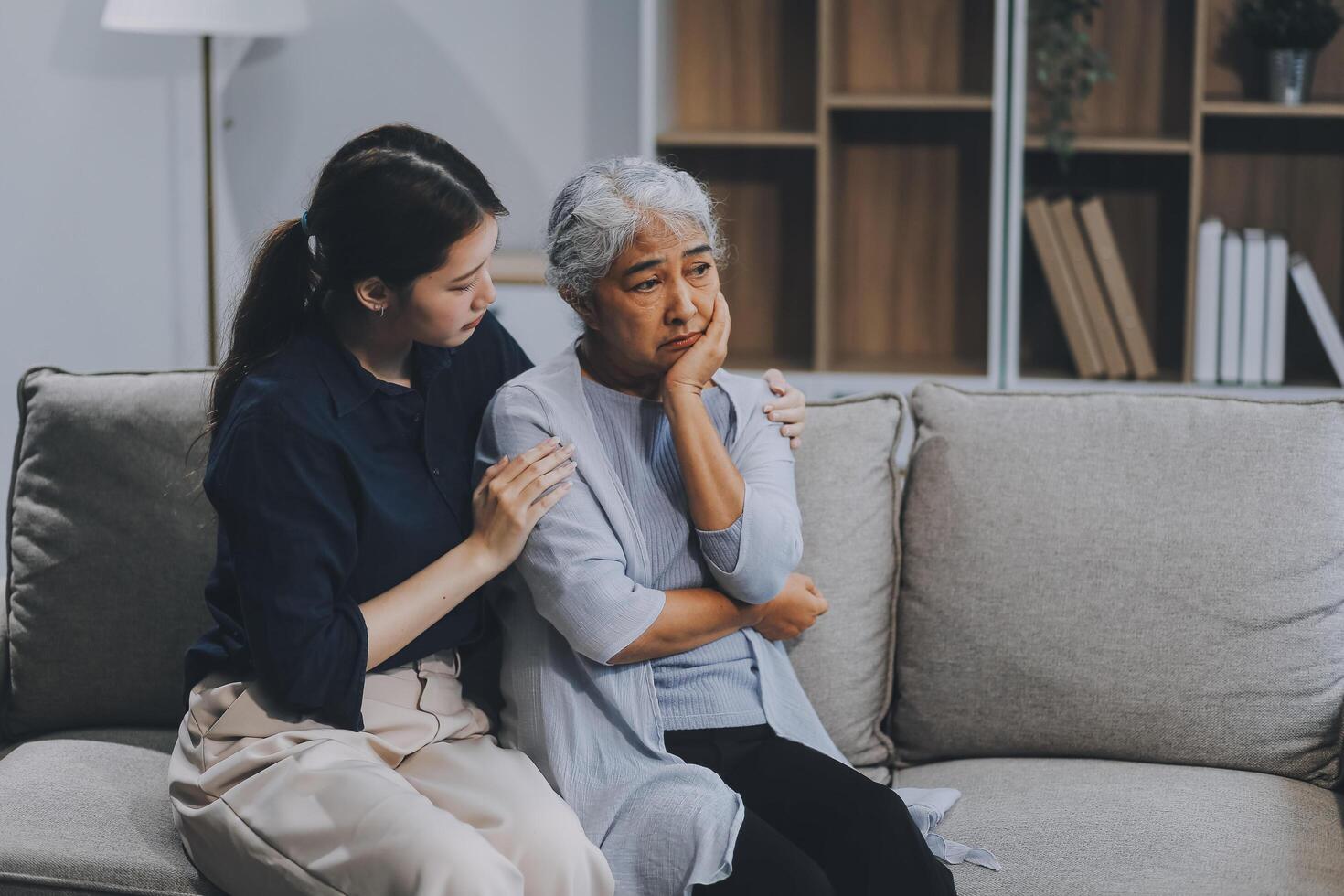 Sad teen granddaughter hugging depressed mature grandmother, giving support, help, comforting, consoling granny. Teenage daughter girl and middle aged mother going through family problems photo