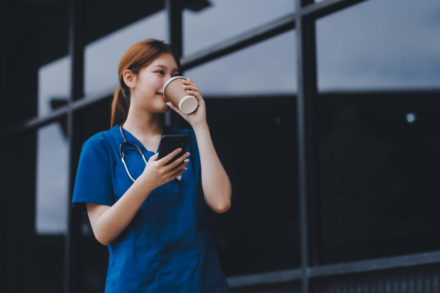Confident nurse on her way to work in a clinic. Pretty female nurse drinking coffee and rest after hard work. The young adult female nurse drinks her coffee as she arrives to work at the hospital. photo
