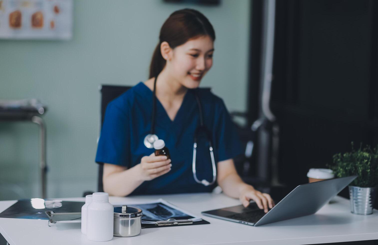 Female doctor writing in a notebook and holding a medicine bottle works at a computer while there were many medicine bottles on the table while sitting at a work desk photo