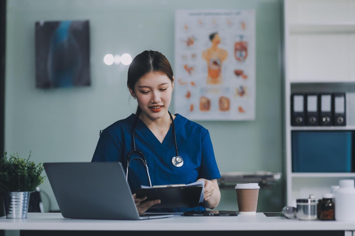 Female doctor writing in a notebook and holding a medicine bottle works at a computer while there were many medicine bottles on the table while sitting at a work desk photo