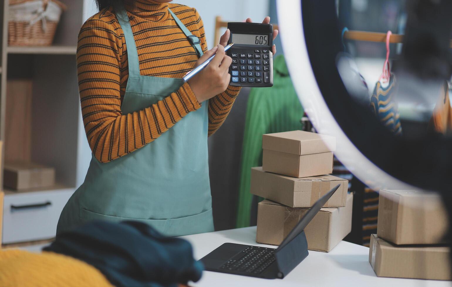 vlogger, blogger small SME business asian beautiful woman using mobile phone call for sell clothes live stream selling online, show product present detail at home office, entrepreneur ecommerce photo