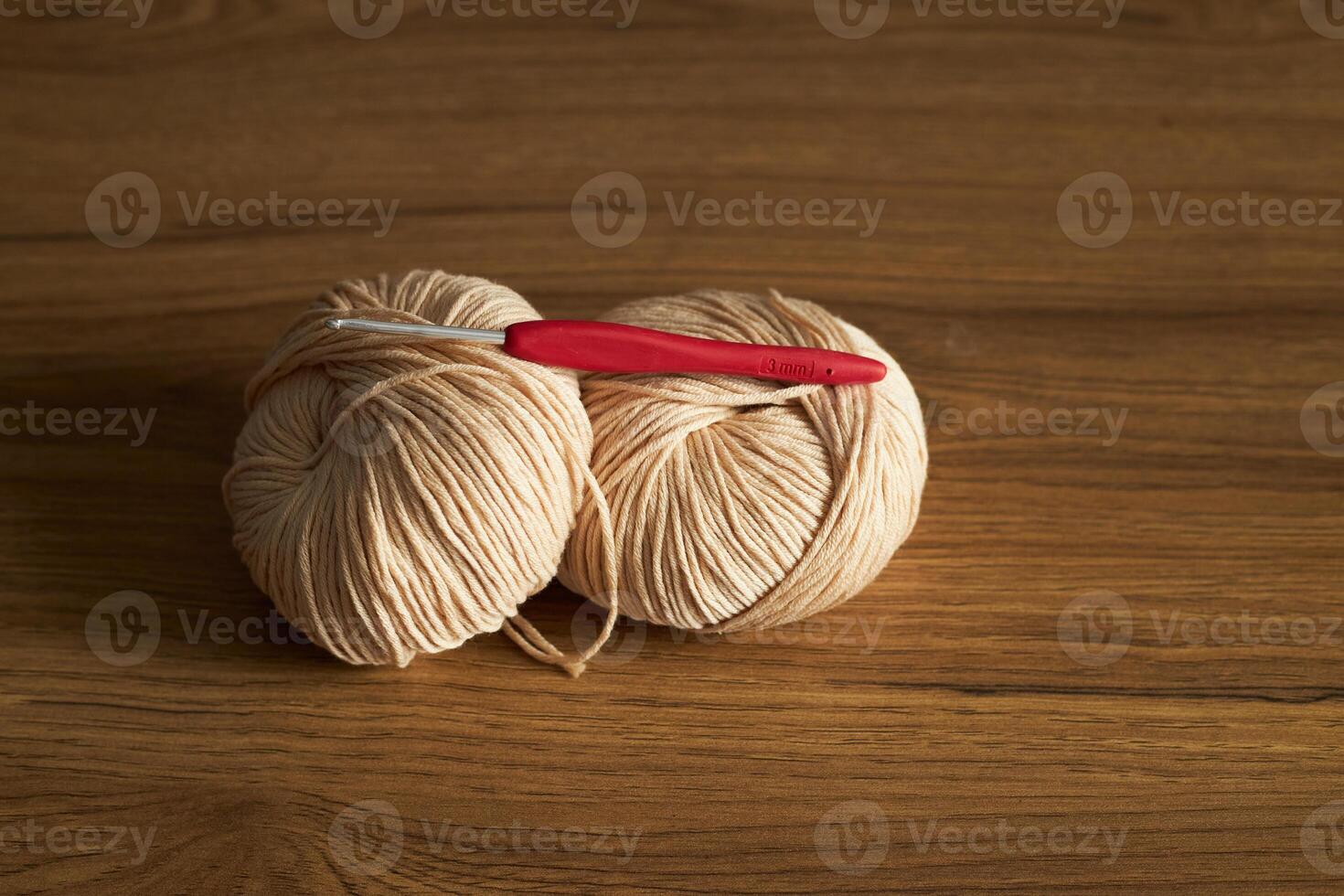 two skeins of yarn for knitting and hook on the table photo