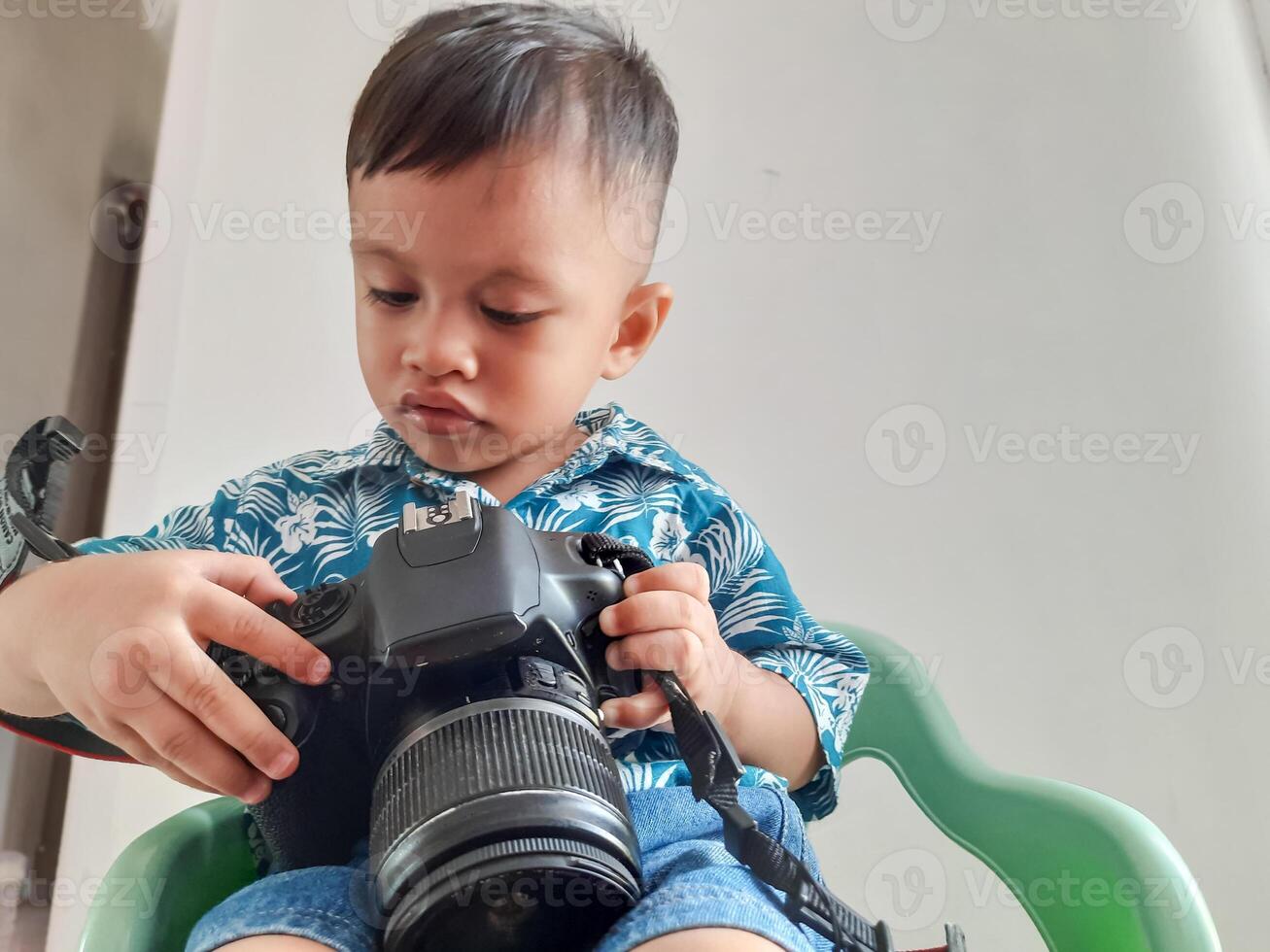 portrait of a toddler boy who is learning new things with a photo camera